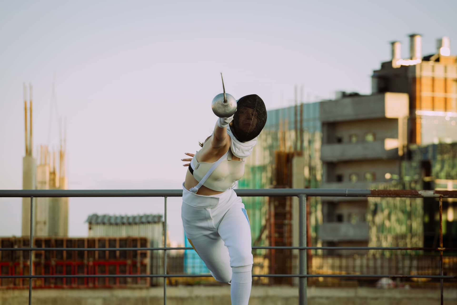 A female fencer showcasing a fleche on a city rooftop